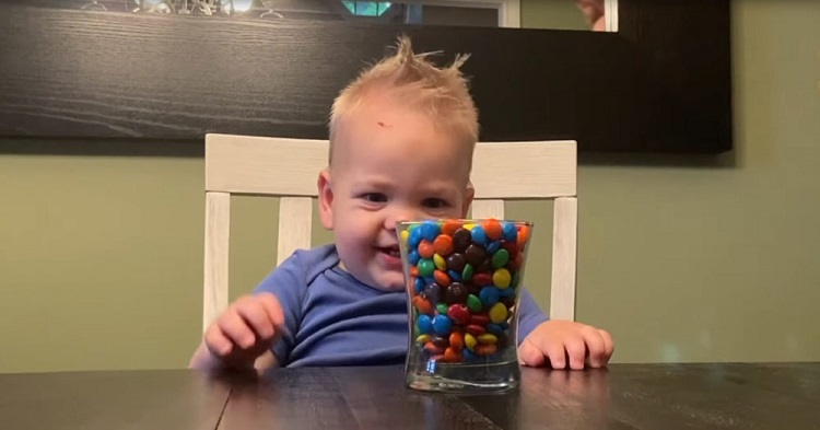 Ce bébé n’a pas le droit de manger des bonbons. Sa mère a placé un bol plein de bonbons devant lui –